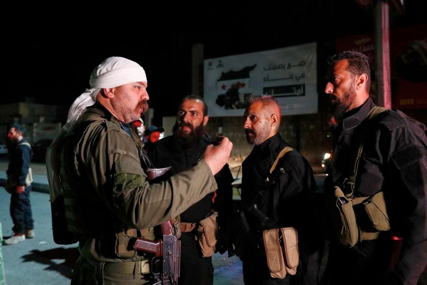 A Druze militia fighter (left) speaks with Syrian security personnel in Jaramana on May 2, 2025.